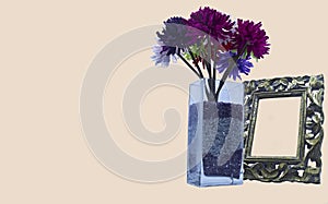 A crystal vase with flowers and a frame on a light background