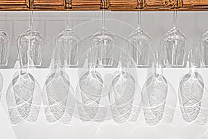 crystal wine glasses hanging on stemware hanger with shadow reflection on white wall photo