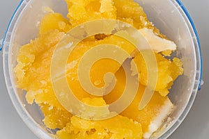 Crystallized honey in plastic round container, top view close-up