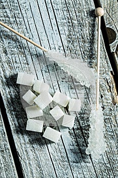 Crystallized sugar on wooden stick and sugar cubes.