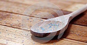 Crystals of blue frit glass falling wooden spoon