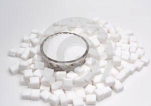 Crystals and cubes of white sugar on white background