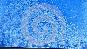 Crystals of snow and ice on the glass and blue sky in the background. Abstract frame, texture and background. Winter