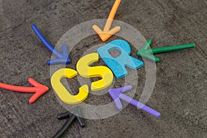 CSR, Corporate social responsibility concept, multi color arrows pointing to the abbreviation CSR at the center of black cement
