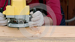 Csucasian carpenter processes wood beam with milling machine.