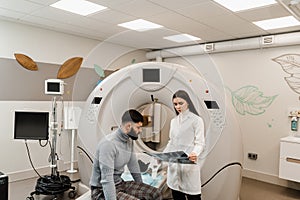 CT Doctor consulting patient and showing x-ray head scan to patient in computed tomography room. CT scan radiologist