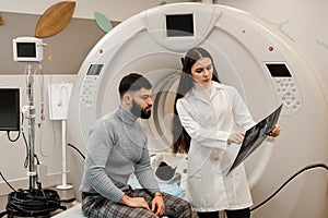 CT scan radiologist showing x-ray of brains to man patient in computed scanning room. CT Doctor consulting patient and