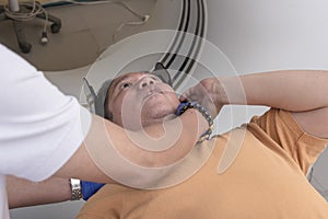 A CT Technologist positioning the neck of a male patient on a holder or cradle. Performing a head CT scan at the hospital