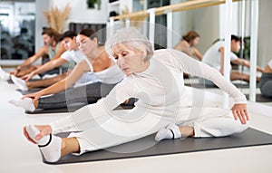 ?ctive senior woman performs exercises on a pilates mat in the hall of a modern fitness studio.