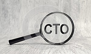 CTO abbreviation and magnifier on wooden background