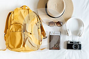 CTravel accessories with beach hat, sunglasses, backpack, camera, headphone and passport on bed at home. Prepare to travel,