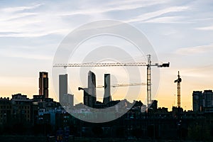 Cuatro Torres Business Area Madrid skyline at sunset with construction cranes and residential buildings with low contrast photo