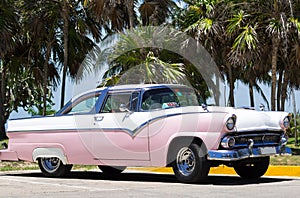 Cuba american white Oldtimer parked under palms