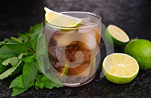 Cuba Libre cocktail with lime and brown rum on a black background.