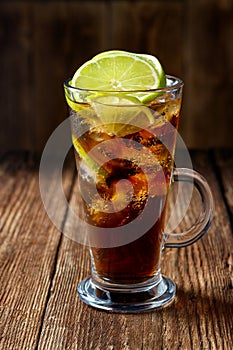 Cuba Libre coctail in a glass with ice and lime