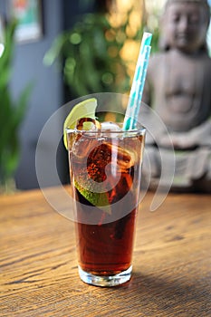 Cuba libre long drink. Cuban cocktail with rum, cola, lime and ice cubes, on a wooden table, selective focus.