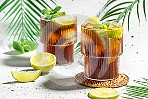 Cuba Libre, long island cocktail with rum, cola, mint and lime in the glass, recipe background. Close up