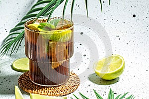 Cuba Libre, long island cocktail with rum, cola, mint and lime in the glass, recipe background. Close up