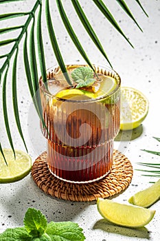 Cuba Libre with rum, cola, mint and lime in the glass on a light background, vertical image. top view. place for text