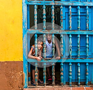 CUBA, TRINIDAD. June 2016: Two children looking out of the window of their house in Trinidad.