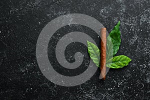 Cuban cigars with leaves on a black stone table