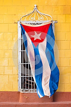 Cuban flag hanging at the window of a colorful house in a street of Trinidad Cuba