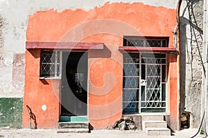 Cuban house with painted exterior next door to houses with no paint