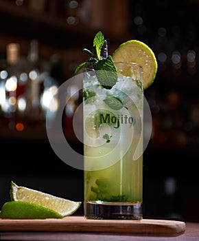 Cuban mojito drink with lemon mint and good herb on a wooden base with a bar background photo
