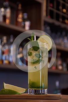 Cuban mojito drink with lemon mint and good herb on a wooden base with a bar background photo