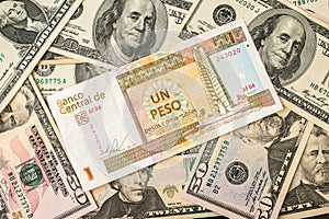 Cuban pesos bill over several dollar bills