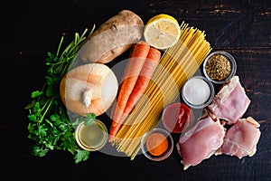 Ingredients for Cuban Style Chicken Noodle Soup on a Dark Wood Background photo