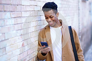 Cuban young man using a smartphone near a urban wall.