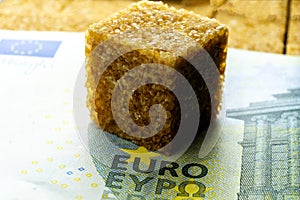 Cube of brown sugar over hubred Euro banknote. World food crisis leds to raising prices for food