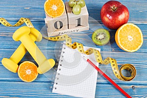 Cube calendar with 1 January, fruits, dumbbells and tape measure, new years resolutions concept