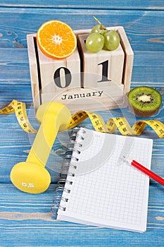 Cube calendar with date of 1 January, fruits, dumbbells and tape measure, new years resolutions