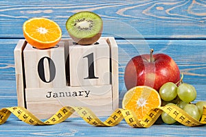 Cube calendar with date of 1 January, fruits and tape measure, new years resolutions concept