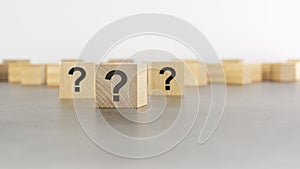 cube with question mark on wooden background. space for text