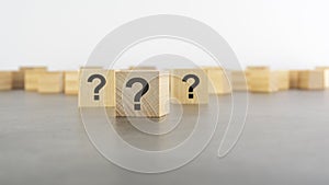 Cube with question mark on wooden background. space for text