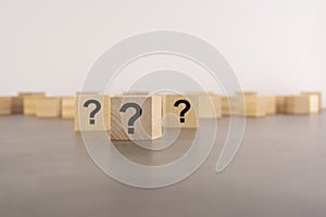 cube with question mark on wooden background. space for text