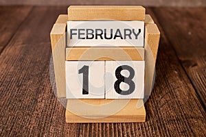 Cube shape calendar for February 18 on wooden surface with empty space for text