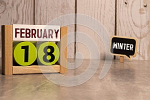 Cube shape calendar for February 18 on wooden surface with empty space for text