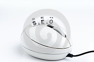 Cube small block with alphabets building the word SEO on minimal white computer mouse on white background using as Search Engine