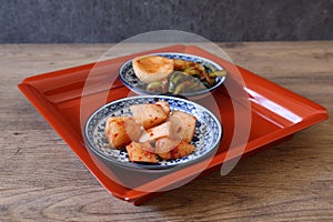 Cubed Radish Kimchi and turnip kimchi on a red tray isolated on a wooden background