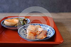 Cubed Radish Kimchi and turnip kimchi on a red tray isolated on a wooden background