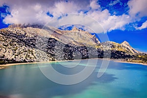 Cuber resevoir, lake, Puig Major, Tramuntana, weather station, trees,rocks, sunlight, low white clouds, turquoise water, Mallorca