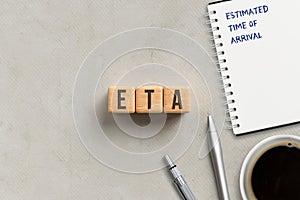 Cubes with acronym ETA and notepad with explanation ESTIMATED TIME OF ARRIVAL