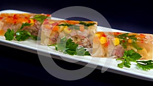 Cubes of aspic with boiled meat, paprika, carrots and maize corn, served with parsley on black background