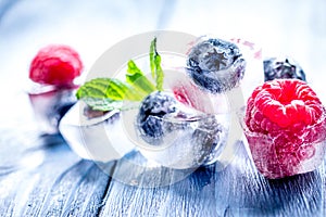 Cubes of berry ice and mint leaf on wooden table beckground