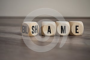 Cubes, blocks or dice with blame and shame on wooden background