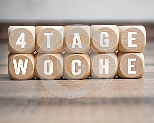 Cubes, blocks or dice with the german words for 4 day week - 4 Tage Woche on wooden background